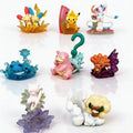 Ensemble de 8 mini-figurines Pokémon posées sur des socles en cristal coloré.